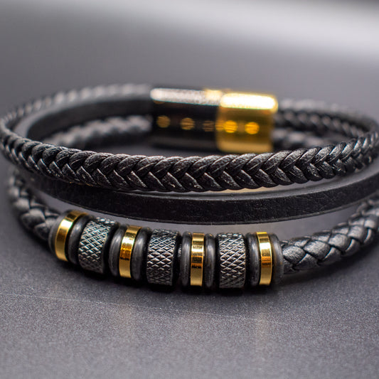 Black braided leather bracelet with metallic beads on a gray background